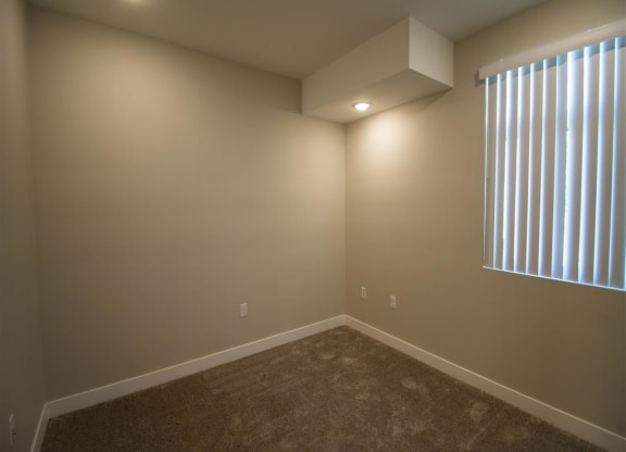 bedroom with a large window and a carpeted floor at Loma Villas Apartments, San Bernardino, CA