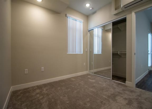 a bedroom with carpeted flooring and a large window at Loma Villas Apartments in San Bernardino, CA