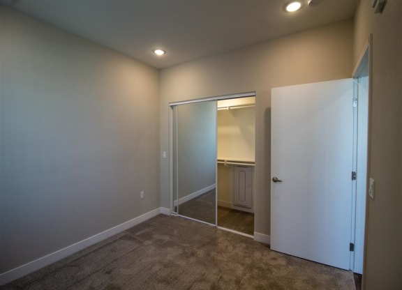 a bedroom with a closet and a mirror at Loma Villas Apartments, San Bernardino
