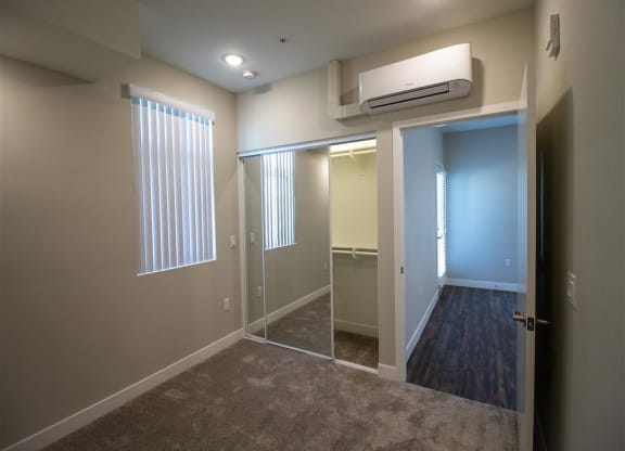 a bedroom with a walk in closet and a large window at Loma Villas Apartments, California, 92408