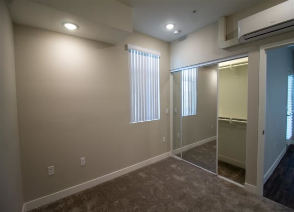 a bedroom with a large window and a mirrored closet at Loma Villas Apartments, California