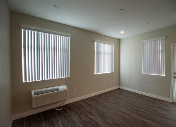 an empty room with three windows and a radiator at Loma Villas Apartments, San Bernardino, CA