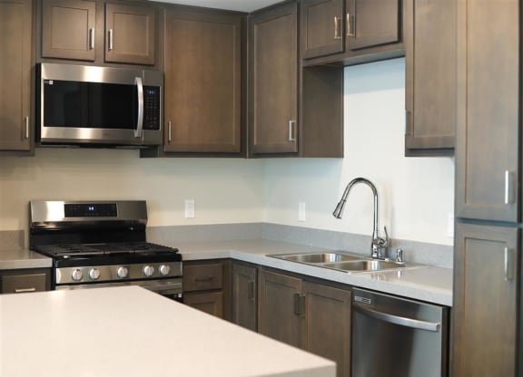 a kitchen with a stove a sink and a microwave at Loma Villas Apartments in San Bernardino, CA