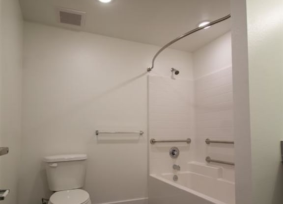 a white toilet sitting next to a bath tub at Loma Villas Apartments, San Bernardino, 92408