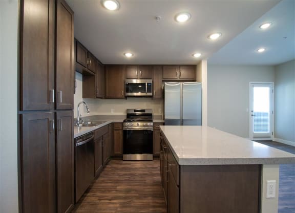 a kitchen with wooden cabinets and a white counter top at Loma Villas Apartments, San Bernardino, 92408