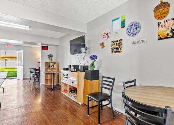 A room with a wooden table and chairs, a TV, and various decorations on the wall. at Canyon Shadows Apartments, Riverside, 92503
