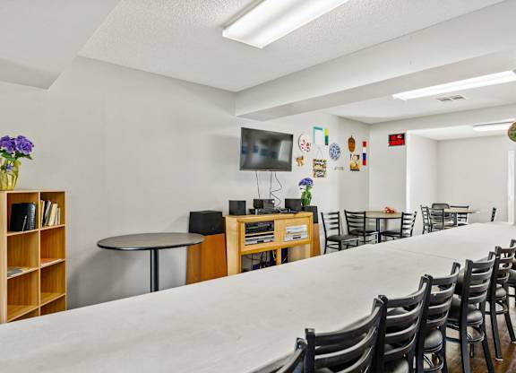 A room with a long table and chairs, a television, and a bookshelf. at Canyon Shadows Apartments, Riverside California 