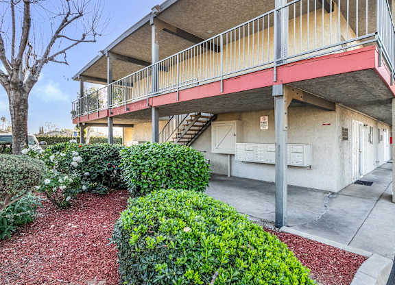 A building with a red awning and a small garden in front. at Canyon Shadows Apartments, Riverside, CA 92503