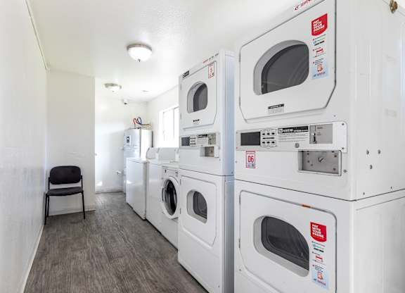 A laundry room with a row of washers and dryers. at Canyon Shadows Apartments, Riverside, CA