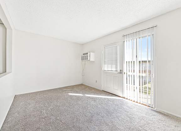A room with a carpeted floor, a window with blinds, and a door with a window. at Canyon Shadows Apartments, California