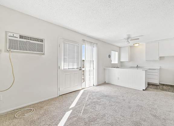 A white room with a window, a fan, and a kitchenette. at Canyon Shadows Apartments, Riverside  