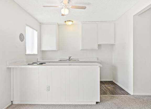 A white kitchen with a fan and cabinets. at Canyon Shadows Apartments, Riverside