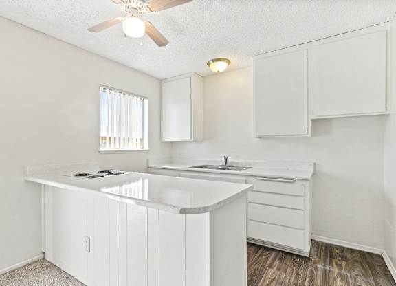 A white kitchen with a window and a ceiling fan. at Canyon Shadows Apartments, California, 92503