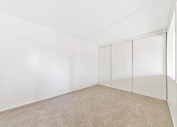 A room with white walls and a carpeted floor. at Canyon Shadows Apartments, California