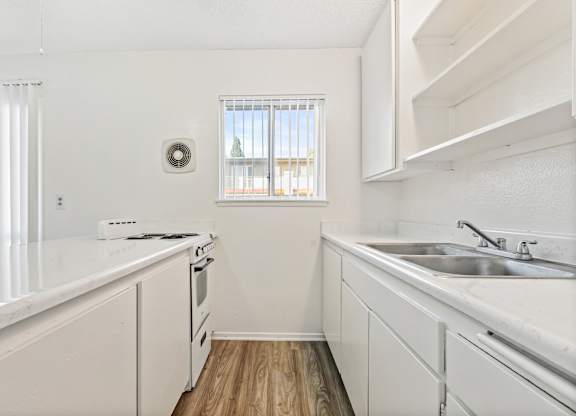A white kitchen with a window and a stove top oven. at Canyon Shadows Apartments, Riverside, CA