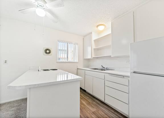 A white kitchen with a fan and a window. at Canyon Shadows Apartments, Riverside California 