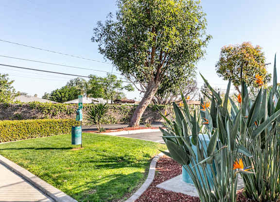 A green pole stands in a grassy area next to a sidewalk. at Canyon Shadows Apartments, Riverside, 92503