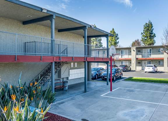 A parking lot with a basketball court and a building in the background. at Canyon Shadows Apartments, Riverside, 92503  