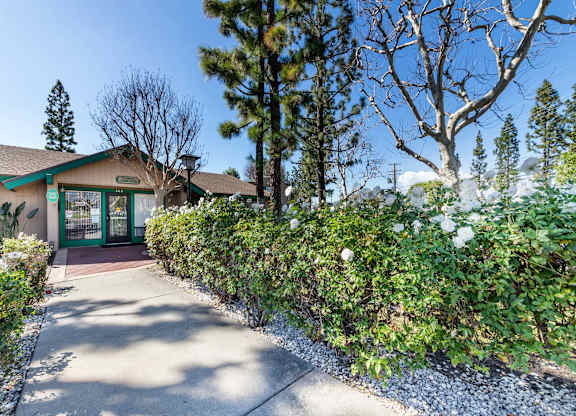 A building with a green roof and a glass door is surrounded by trees and bushes. at Heritage Park, Rialto