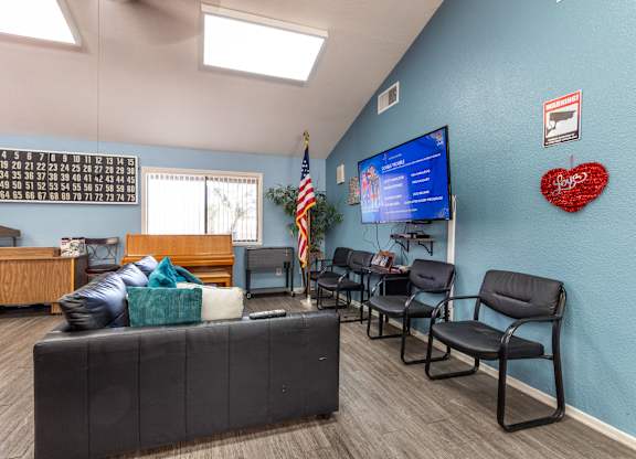 A waiting room with a sofa, chairs, and a TV screen. at Heritage Park, Rialto