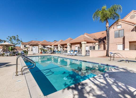 A swimming pool in front of a building with a palm tree. at Whispering Fountains Diamond Bar, Diamond Bar, 91765