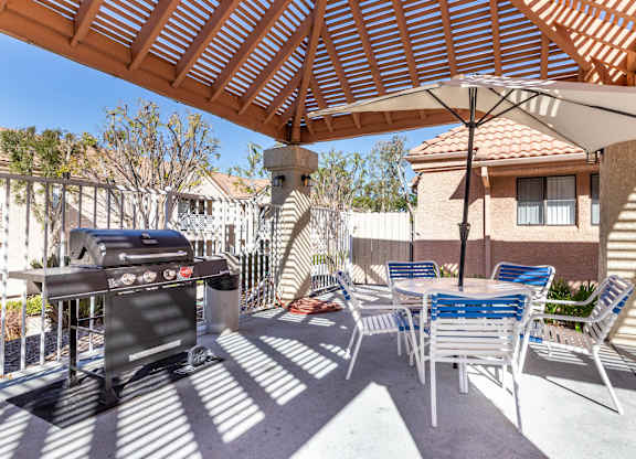 A patio with a grill and chairs under a wooden roof. at Whispering Fountains Diamond Bar, Diamond Bar, CA