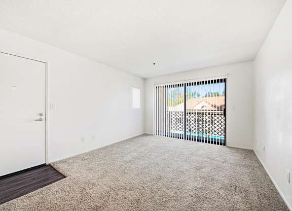 A room with a carpeted floor and a sliding glass door leading to a balcony. at Whispering Fountains Diamond Bar, Diamond Bar, CA 91765