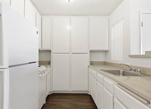 A white kitchen with a refrigerator, dishwasher, and sink. at Whispering Fountains Diamond Bar, California
