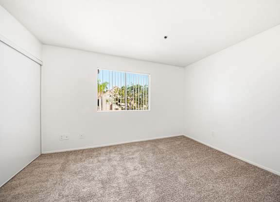 A room with a window showing a view of trees and a building outside. at Whispering Fountains Diamond Bar, California