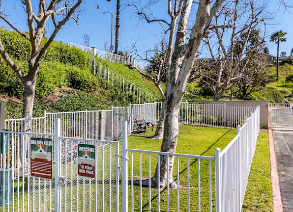 A white fence surrounds a green area with a sign that says at Whispering Fountains Diamond Bar, California, 91765