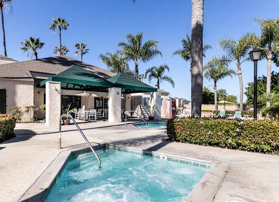A pool area with a hot tub and a green canopy. at Whispering Fountains Lakewood, California