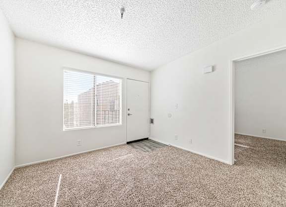 A room with a carpeted floor and a window with blinds. at Whispering Fountains Lakewood, Lakewood Bar