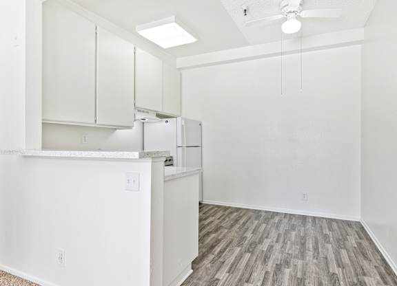 A kitchen area with a refrigerator, cabinets, and a ceiling fan. at Whispering Fountains Lakewood, Lakewood Bar California