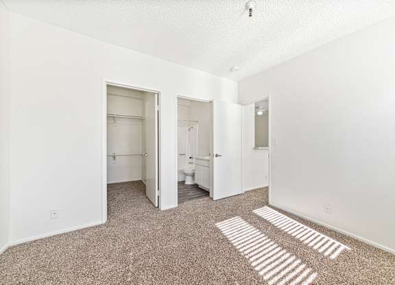 A white room with a carpet and a toilet in the corner. at Whispering Fountains Lakewood, Lakewood Bar California