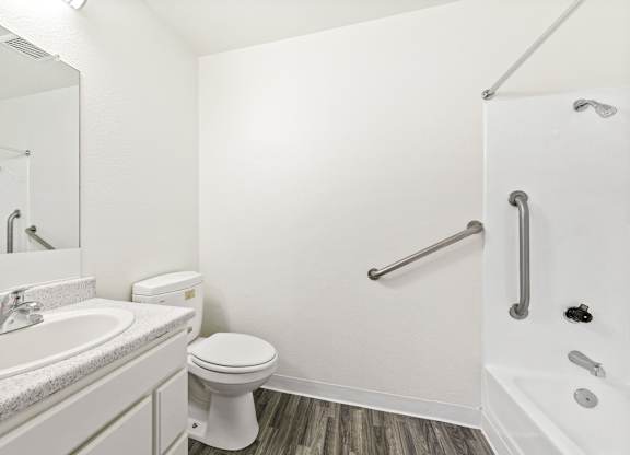 A white bathroom with a toilet and sink at Whispering Fountains Lakewood, Lakewood Bar, CA