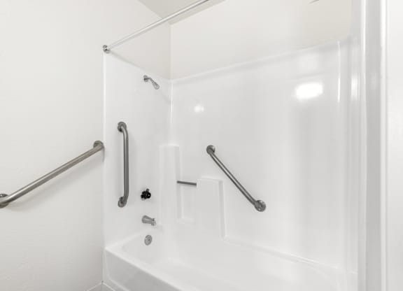 A white bathroom with a glass shower door and a white tub. at Whispering Fountains Lakewood, Lakewood Bar, 90805