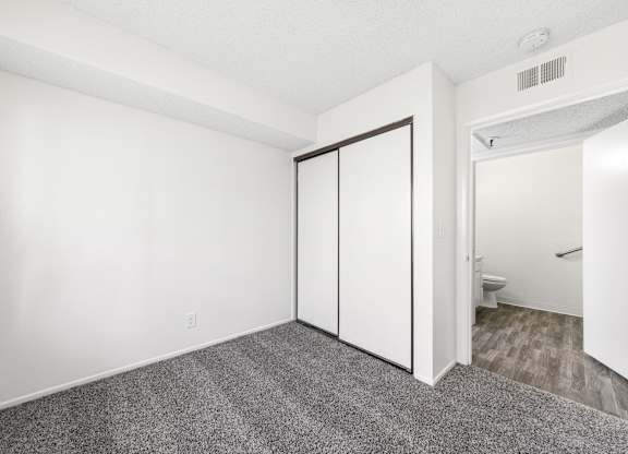 A room with a carpeted floor and a white door. at Whispering Fountains Lakewood, Lakewood Bar, CA