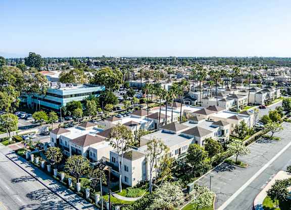 A suburban neighborhood with houses and a large building in the background. at Whispering Fountains Lakewood, Lakewood Bar California