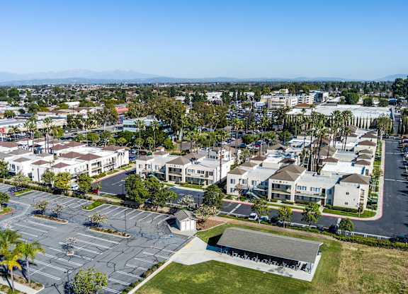 A large parking lot is surrounded by apartment buildings. at Whispering Fountains Lakewood, Lakewood Bar California