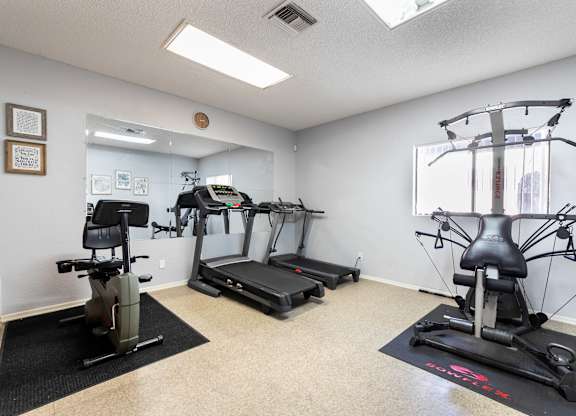 Gym with a treadmill, elliptical trainer, and a stationary bike at Whispering Fountains Riverside, California 
