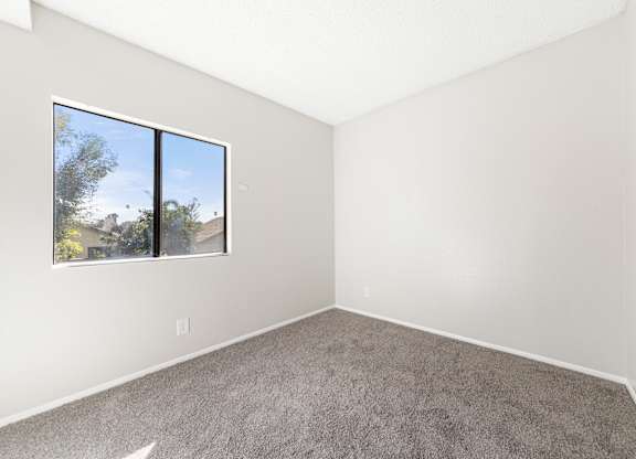 Modern Living Room with a large window and carpeted floor at Whispering Fountains Riverside, California 
