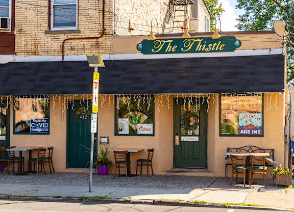 The Thistle restaurant has tables and chairs outside. at Vermella Lyndhurst apartments, New Jersey, 07071