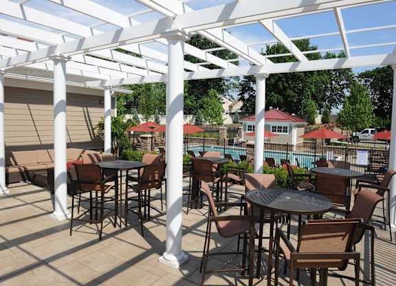 A patio with tables and chairs under a white pergola at Vermella Lyndhurst apartments, Lyndhurst 07071