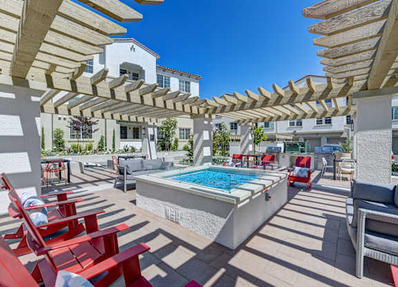 A pool surrounded by red chairs and wooden pergolas.