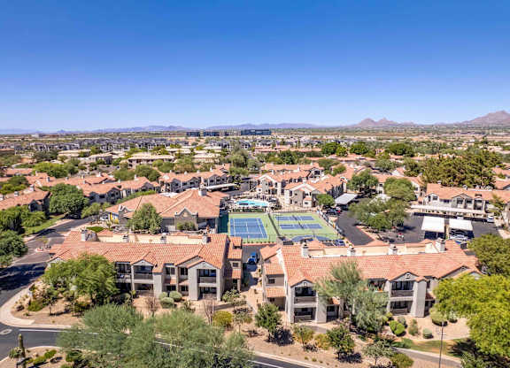 A large building with a tennis court in the middle of a residential area.