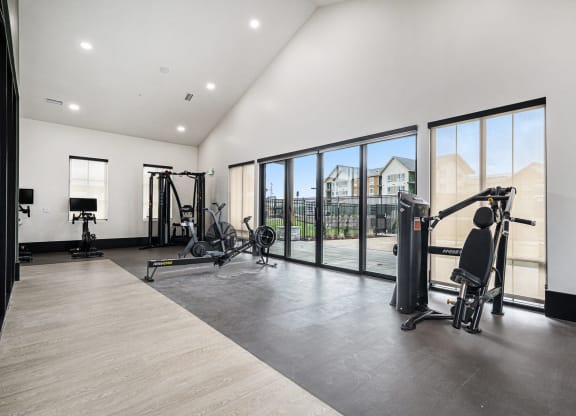 a workout room with weights and cardio equipment and large windows
