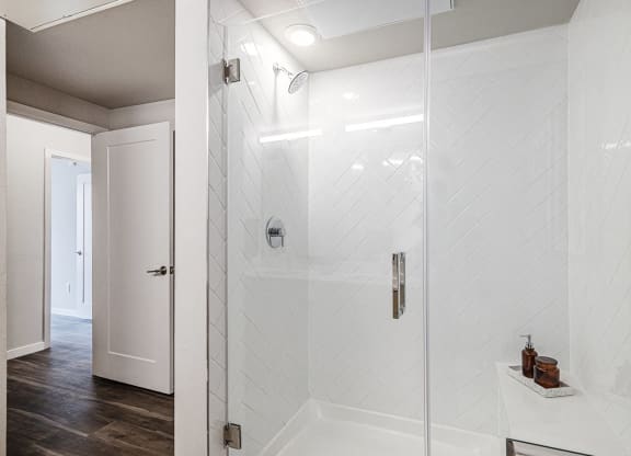 a walk in shower in a bathroom with white tile
