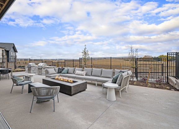 the outdoor patio has a fire pit and chairs and couches