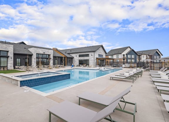 a swimming pool with lounge chairs in front of a building