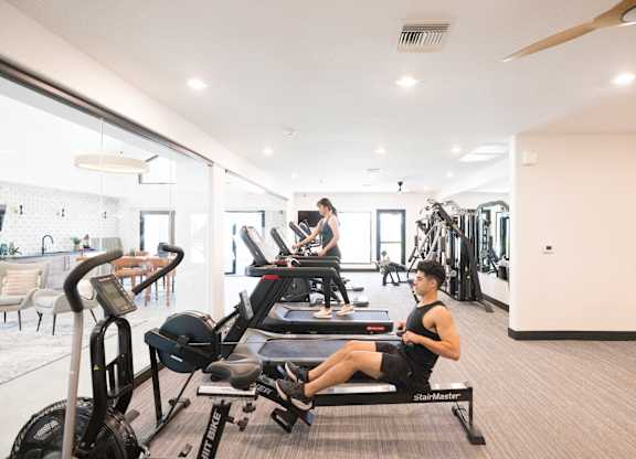 A man is working out on a rowing machine in a spacious gym.